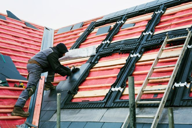 a-roofer-replacing-the-tiles-on-a-house-roof-54Z9HNX