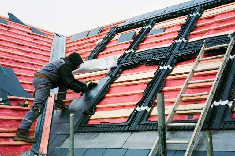 a-roofer-replacing-the-tiles-on-a-house-roof-54Z9HNX